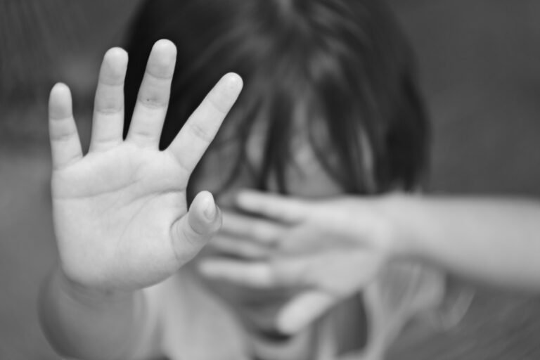 Grayscale shot of a child stopping with his hand
